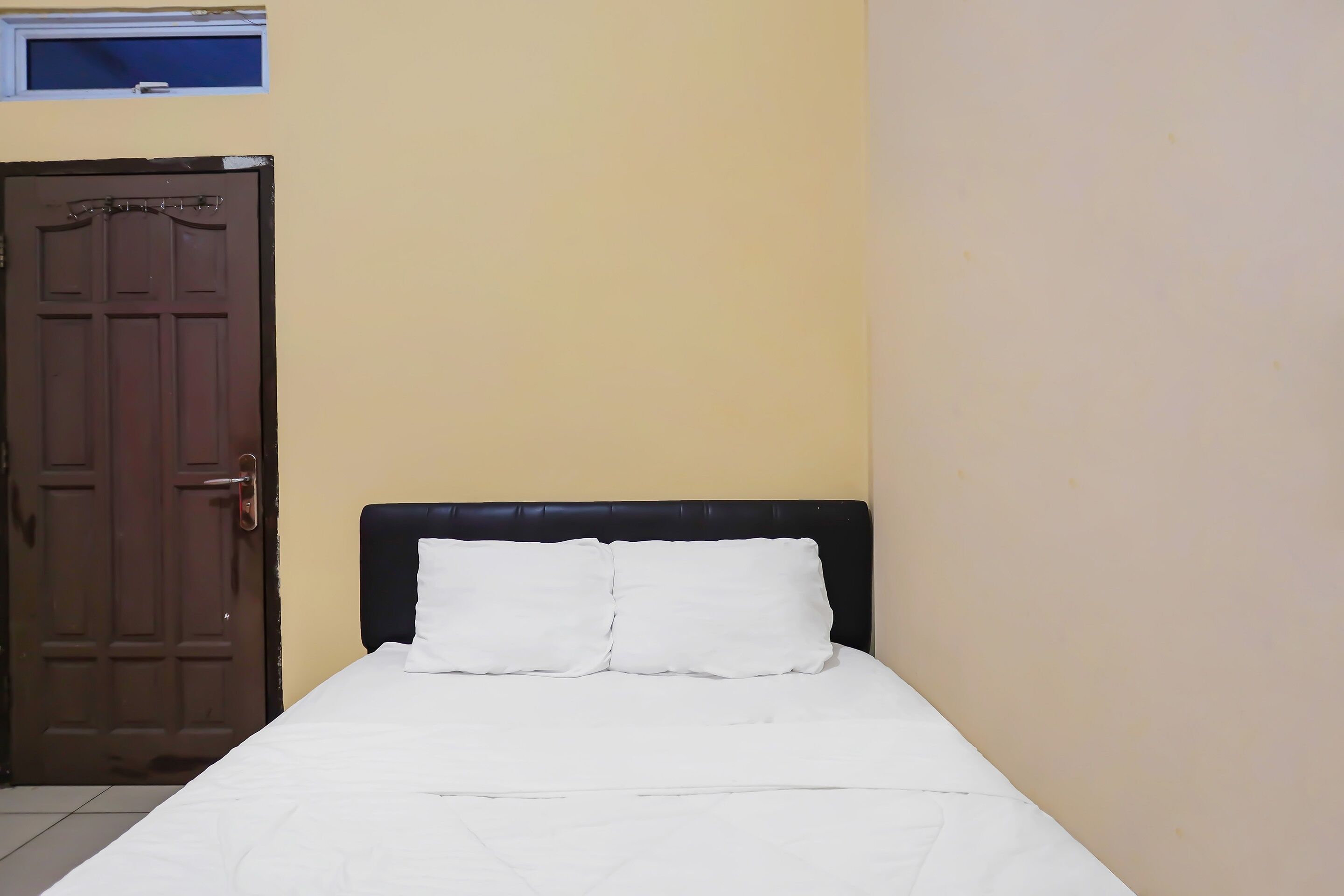 Una habitación con cama, puerta y ventana.