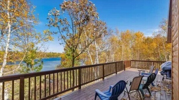 A wooden deck with a view of a lake and autumn trees. - Gorgeous Lake View with Pontoon!

 (Park Rapids)