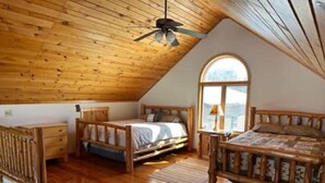 A cozy attic bedroom with wooden floors, a sloped ceiling, and a large window. - Gorgeous Lake View with Pontoon!

 (Park Rapids)