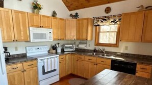 A kitchen with wooden cabinets, a microwave, a stove, a sink, and a dishwasher. - Gorgeous Lake View with Pontoon!

 (Park Rapids)