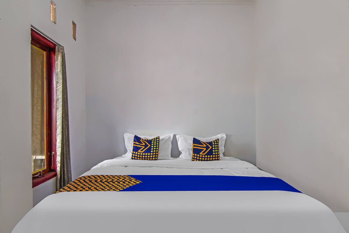 A bedroom with a bed, two pillows with a geometric pattern, and a blue and yellow bedspread.