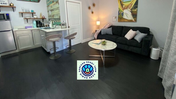 Espai habitable compacte amb zona de cuina, menjador i saló amb sofà i cadires.