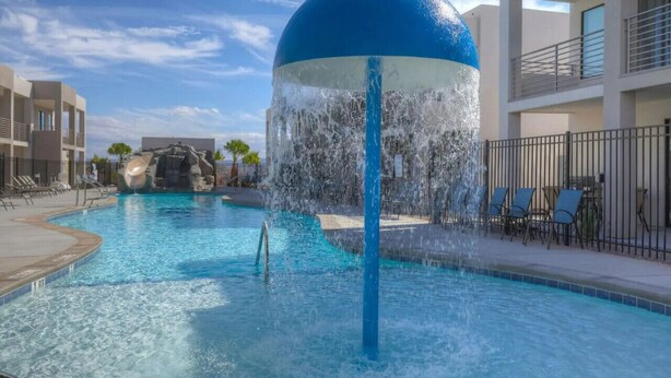 Piscina com um recurso de fonte de água e cadeiras de descanso.