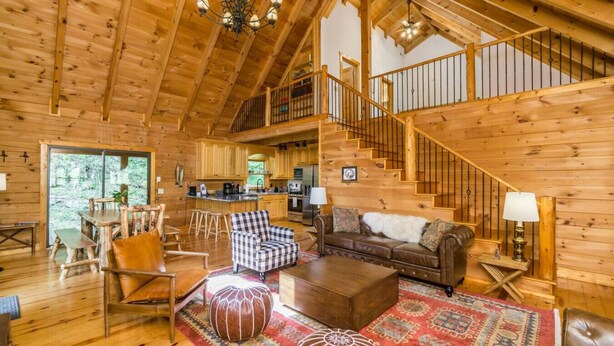 A spacious wooden cabin with a large living area, a kitchen, and a staircase leading to an upper level.