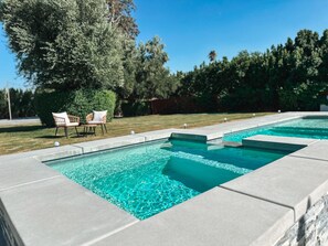 Una piscina al aire libre, sombrillas, sillones reclinables de piscina