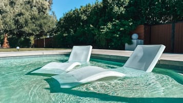 Een buitenzwembad, parasols voor strand/zwembad