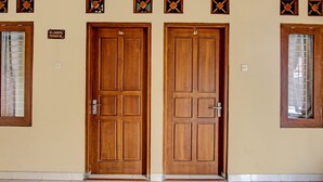 Un pasillo con dos puertas de madera, un letrero sobre la puerta izquierda y una ventana en la pared izquierda.