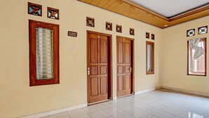 Una habitación amplia con suelo de baldosas, puertas de madera y una ventana con persianas.