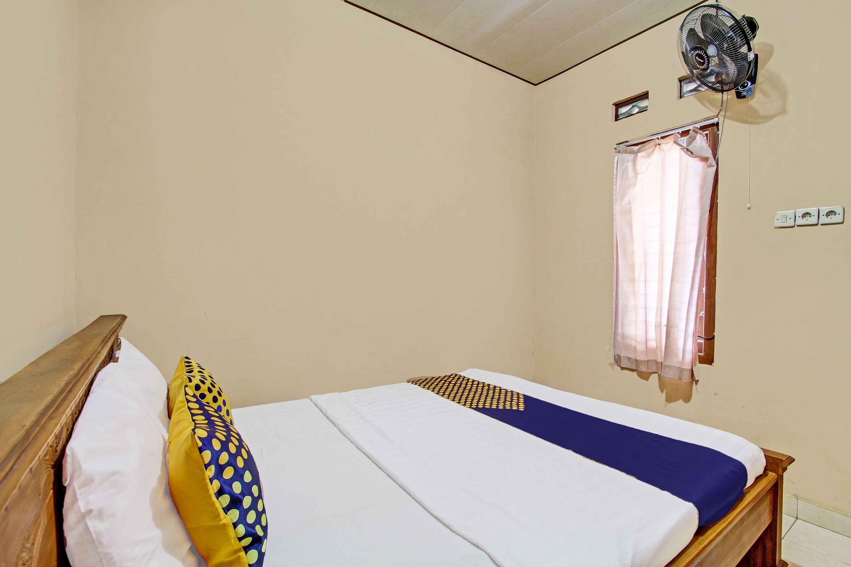 Un lit simple avec une tête de lit en bois, une literie blanche et bleue, un oreiller jaune et une couverture bleue.