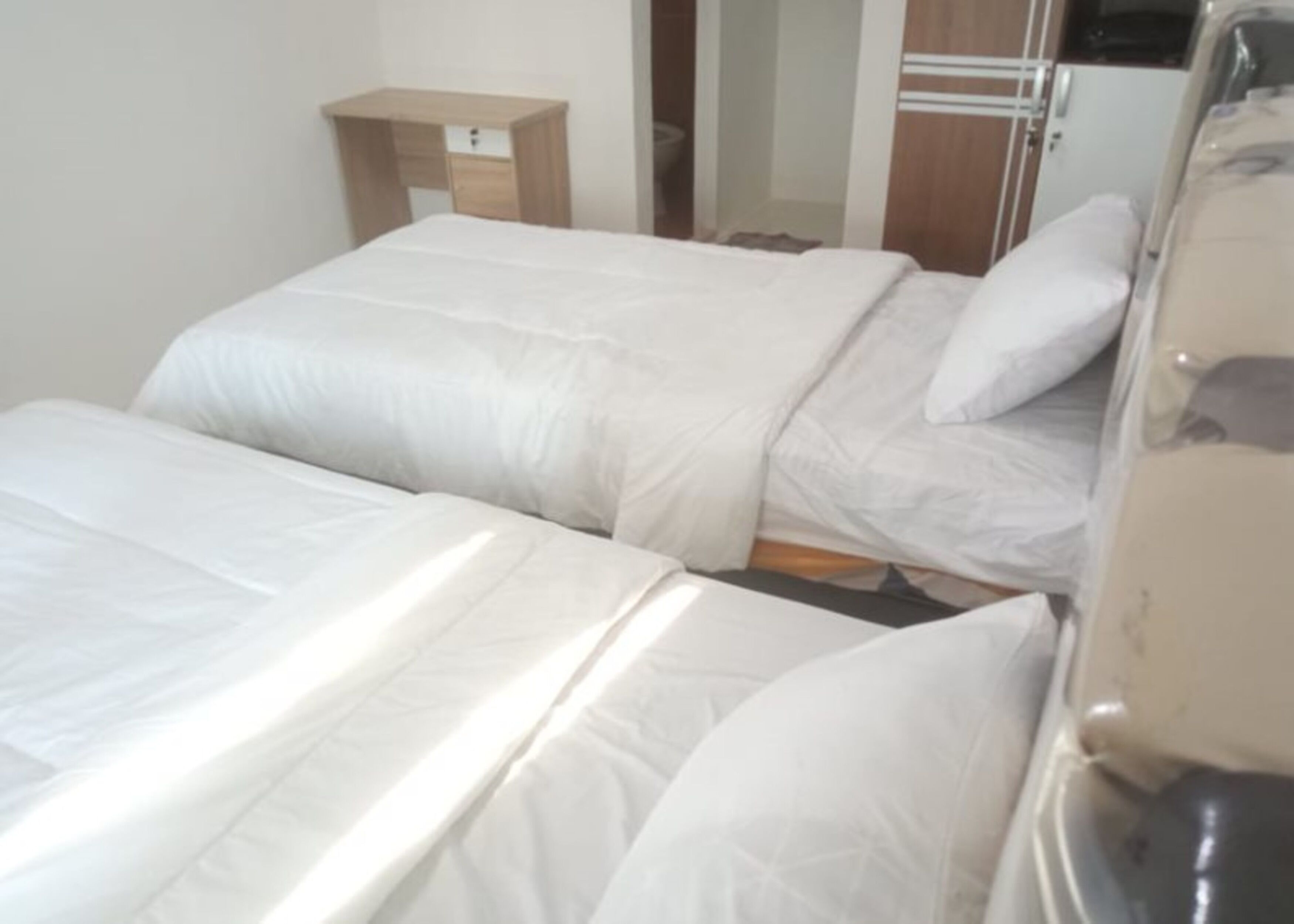 A hotel room with two beds, a wooden nightstand, and a mirror.