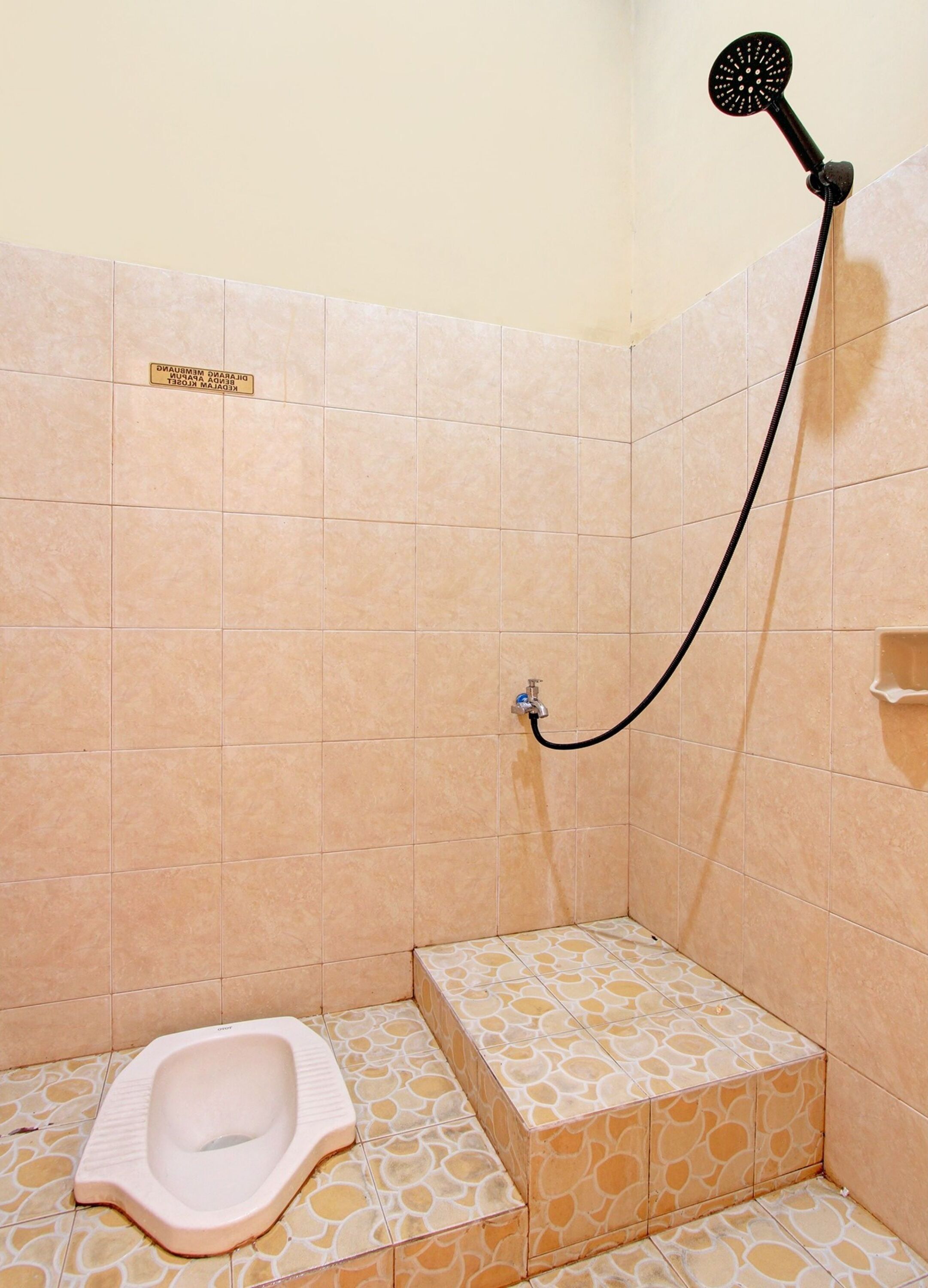 A small bathroom with a toilet, a shower, and a sign on the wall.