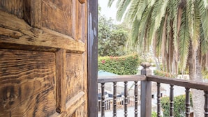 Un balcon en bois, avec un palmier et une vue sur une piscine.