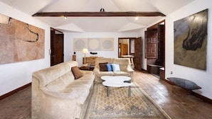 Un salon spacieux avec un plafond haut, une grande moquette et un banc en bois.