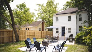 A backyard with a patio area, outdoor furniture, and a barbecue grill.