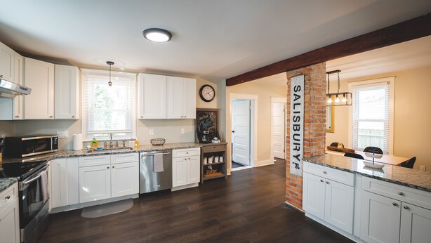 A modern kitchen with white cabinets, a brick accent wall, and a large island.