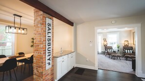 A kitchen with a brick accent wall, wooden cabinets, and a hanging light fixture.