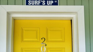 A bright yellow door with the number 203 and a keypad lock. Above the door, a sign reads "SURF'S UP ST." - Surfs Up - 1 Block to Beach & Walk to Dining (Flagler Beach)
