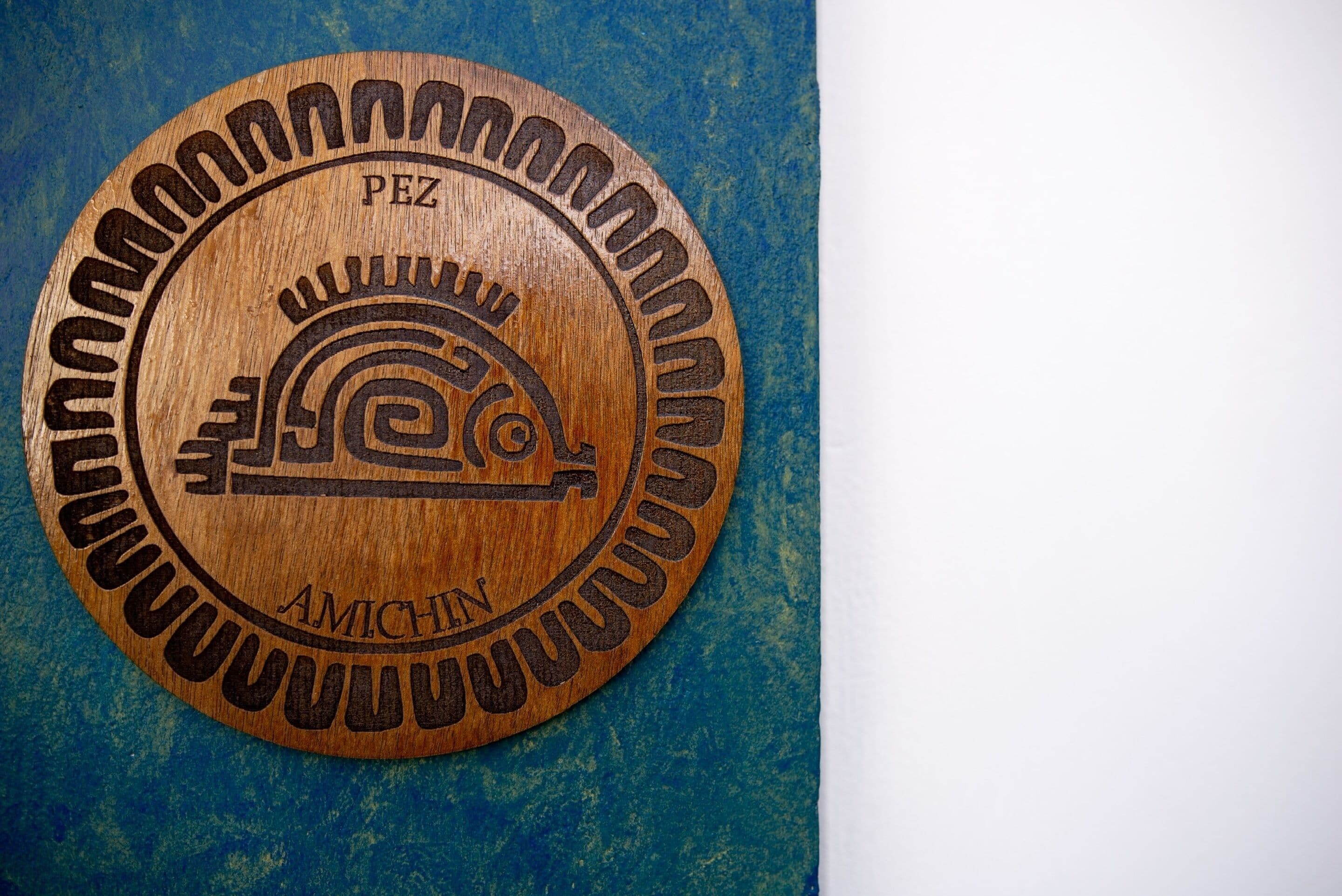 A circular wooden plaque with carved text and a symbol.