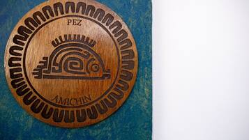 A circular wooden plaque with carved text and a symbol.