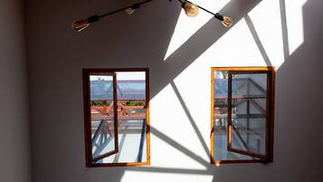 Una habitación con dos ventanas, un candelabro en el techo y una mesa redonda.