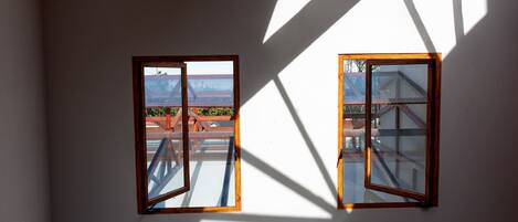 Una habitación con dos ventanas, un candelabro en el techo y una mesa redonda.