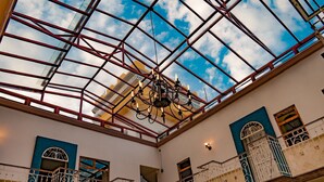 Un atrio de varios niveles con techo de vidrio, barandillas de hierro ornamentadas y un candelabro.