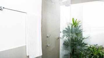 Un baño moderno con cabina de ducha de vidrio, un perchero y plantas en macetas.