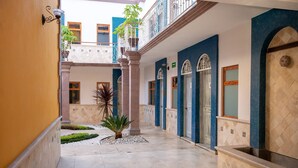 Pasillo de hotel con suelo de baldosas, columnas y una pequeña planta.