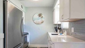 A compact kitchen with a stainless steel refrigerator, a microwave, and a sink. - Indian Rocks Gem: Walk to Beach and Dining from Cozy retreat! (Indian Rocks Beach)