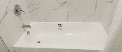 Ein Badezimmer mit weißer Marmorwand und einer weißen Badewanne.
