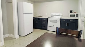 A compact kitchen with a refrigerator, stove, microwave, and dark cabinets. - Village Inn Motel (Rockport)