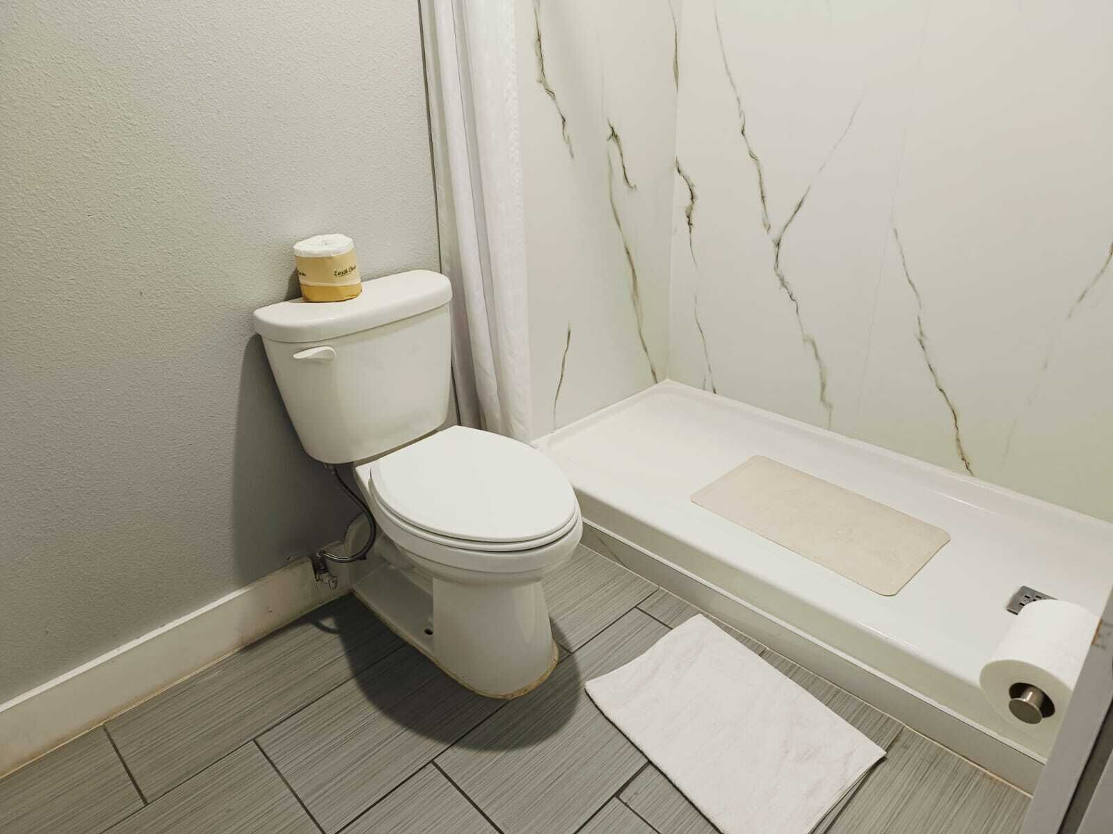 Une salle de bain équipée de toilettes, d’une baignoire et d’un rideau de douche.