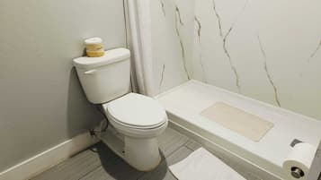 Une salle de bain équipée de toilettes, d’une baignoire et d’un rideau de douche.