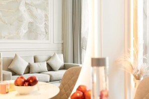 Uma sala de estar moderna com um sofá, uma mesa com uma tigela de frutas e um vaso com plantas secas.