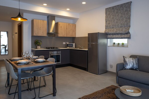 Una cocina moderna con armarios de madera, microondas integrado y refrigerador de acero inoxidable.