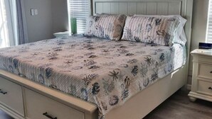 A bedroom with a bed, a nightstand, a ceiling fan, and a window with blinds.