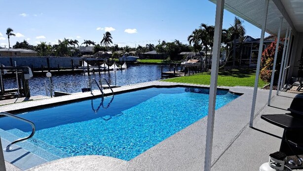 A swimming pool with clear blue water, a dock, and a gas canister on the right.