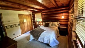 A log cabin bedroom with a bed, a dresser, and a window with blinds. - Log Home w/ Shared Beach and Game Room. (Walker)