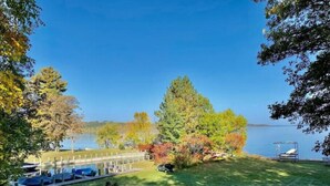 A lakeside view with a dock, a grassy area, and a chair by the water. - Log Home w/ Shared Beach and Game Room. (Walker)