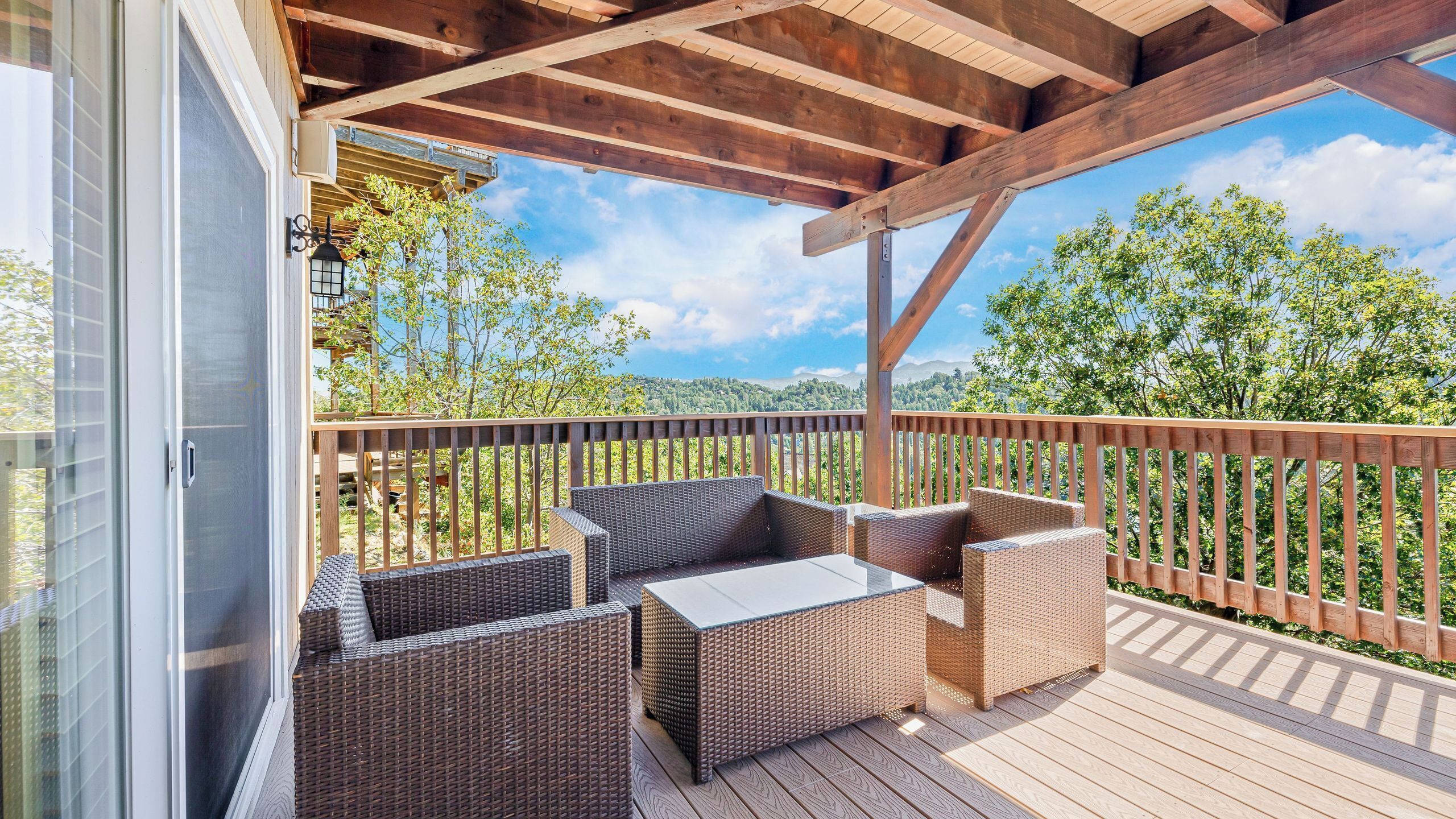 Una terraza cubierta con mobiliario de mimbre y barandilla de madera.