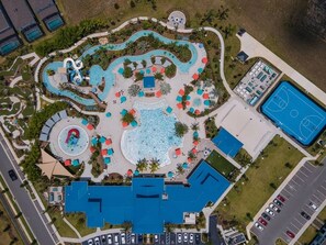 An aerial view of a resort with multiple swimming pools, a basketball court, and a parking area. - Luxury 8BR Retreat | Private Pool, Spa & Resort Amenities | Near Disney (Davenport)