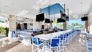 An outdoor bar area with a long counter, blue chairs, and a Christmas tree. - Luxury 8BR Retreat | Private Pool, Spa & Resort Amenities | Near Disney (Davenport)