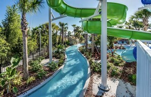 Ein Wasserpark mit einer gewundenen Wasserrutsche, Palmen und einem Poolbereich.