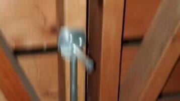 Uma porta de madeira com maçaneta de metal e dobradiça visível.