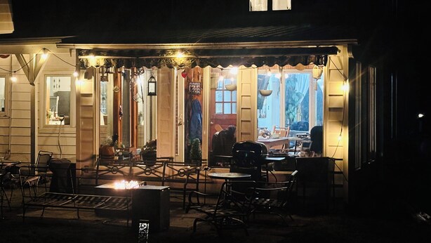 A building with a covered outdoor seating area, a fire pit, and a window with curtains.