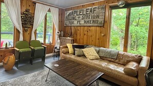 A cozy cabin interior with a wooden wall sign, a leather sofa, a coffee table, and a rustic decor.