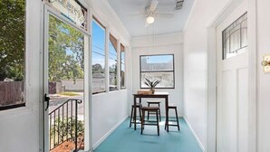 A narrow hallway with a teal floor, a ceiling fan, and a table with chairs. - Redstick Cottage (Baton Rouge)