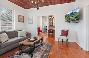 A living room with a sofa, coffee table, and a TV mounted on the wall. - Redstick Cottage (Baton Rouge)