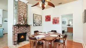 A dining area with a brick fireplace, wooden dining table, and chairs. - Redstick Cottage (Baton Rouge)