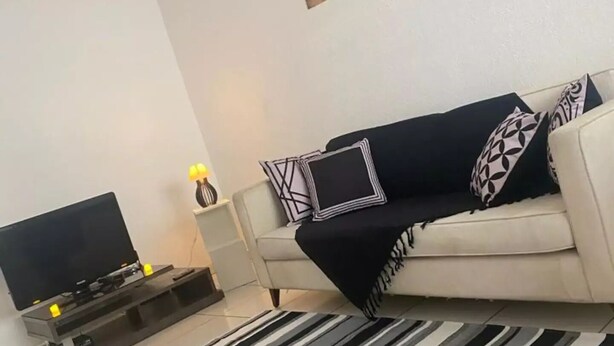 A living room with a sofa, a flat-screen TV, a rug, and wall art.